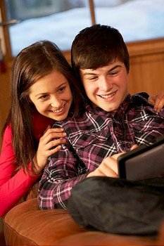 Teenage Couple Relaxing On Sofa With Laptop