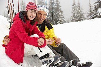 Middle Aged Couple Eating Sandwich On Ski Holiday In Mountains