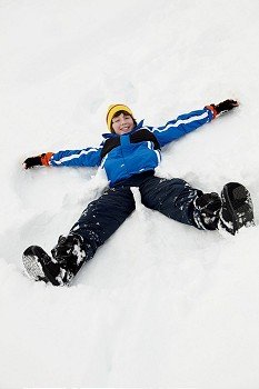 Young Boy Making Snow Angel On Slope