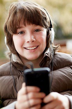 Boy Wearing Headphones And Listening To Music On Smartphone Wearing Winter Clothes