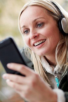 Woman Wearing Headphones And Listening To Music On Smartphone Wearing Winter Clothes