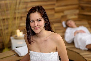 Close -up of woman wrapped in towel sitting at spa room