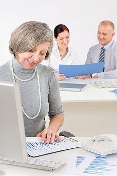 Senior executive woman looking at charts during meeting with team colleagues