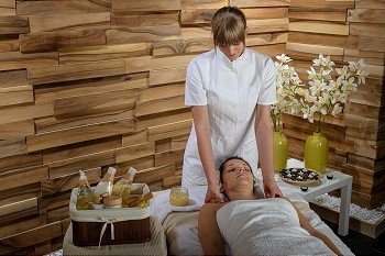 Woman enjoying neck massage from female masseur at luxury spa