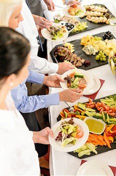 Business people around buffet table catering food at company event