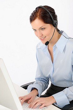 Friendly help desk woman at call center sitting behind computer