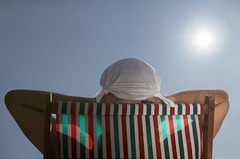 Man sunbathing in deckchair with handkerchief hat on his head
