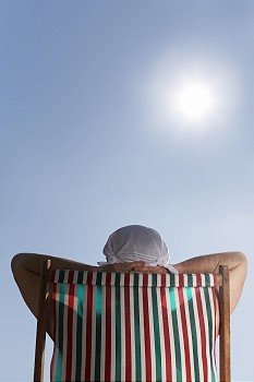 Man sunbathing in deckchair with handkerchief hat on his head