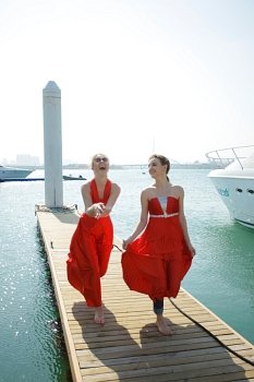 Two women in red dresses walking on pontoon