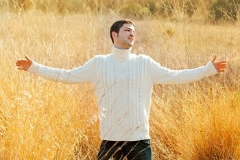 Autumn winter man in outdoor golden grass field with turtleneck sweater open arms