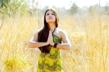 Asian indian woman praying hands  in golden field with green dress