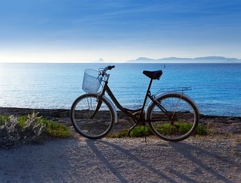 Bicycle in formentera beach on Balearic islands with Ibiza sunset background