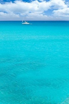 Balearic mediterranean turquoise sea with sailboat under blue sky