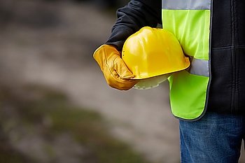 builder with yellow helmet and working gloves on building site