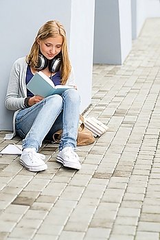 Teenage student girl study siting ground outside university building