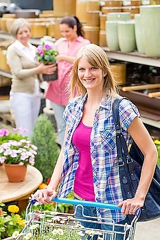 Young woman with trolley shopping for flowers at garden centre