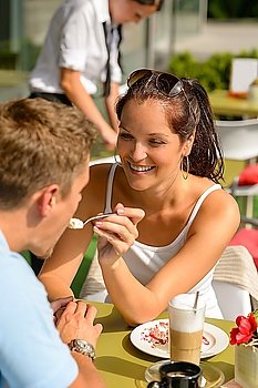 Woman feeding man cheesecake at cafe couple flirting romantic happy