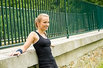 Sportive girl resting against fence after workout happy smiling workout