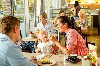 Father and mother feeding child cake cafe woman man eating