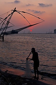 Fisherman and Kochi chinese fishnets on sunset. Fort Kochin, Kochi, Kerala, India