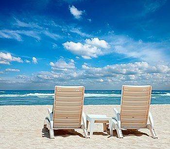 Two sun beach chairs on shore near ocean