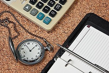 pocket watch and calculator on a cork board