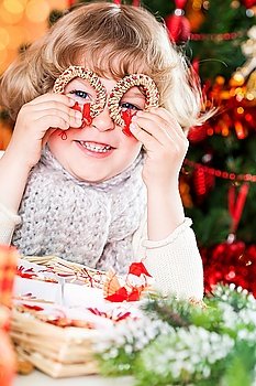 Funny smiling child holding handmade eco decorations against Christmas lights