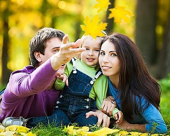 Happy family playing against blurred maple leaves background in autumn park