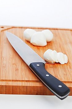 Sliced mozzarella with knife on wooden board