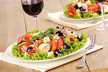 Greek salad and glasses of red wine
