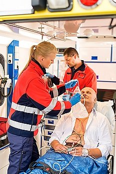 Paramedic putting oxygen mask on patient ambulance sick emergency