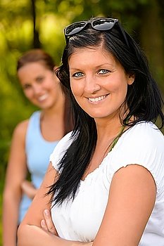 Mother smiling with teen daughter in background parenting outdoors relaxing