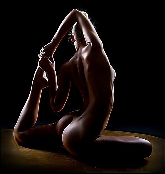 Beautiful naked female body over black background. Wellness. Fitness. Yoga