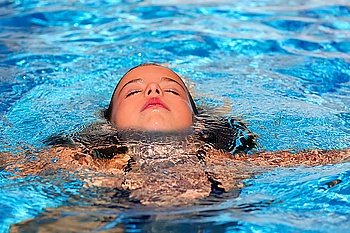 beautiful relaxed kid girl at the pool with face in water surface