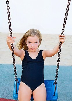 blond children girl swinging on blue swing in black swimsuit on summer vacations