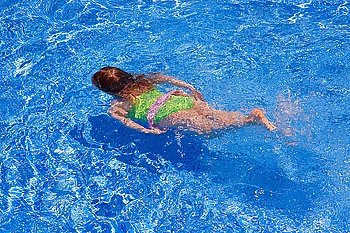 children gilr swimming underwater in blue tiles pool