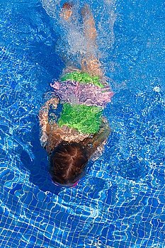 children gilr swimming underwater in blue tiles pool