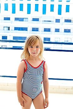 Blond kid girl with summer swimsuit in blue apartment balconade