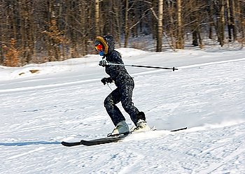 The young girl on skis goes from mountain in a spotty suit