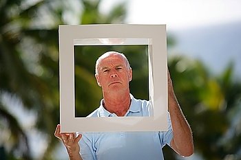 Senior man holding up a square frame