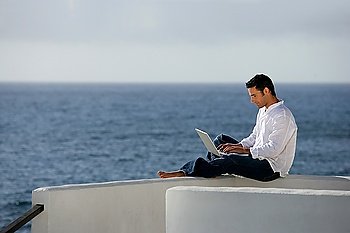 Man with computer in front of the sea