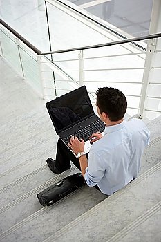 Businessman sitting on some steps with a laptop