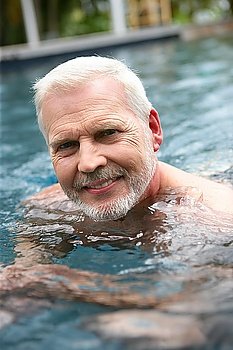 Grey-haired man swimming in the pool
