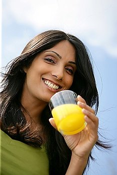 Smiling woman drinking a glass of orange juice