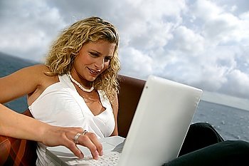 Woman sat at the coast with laptop