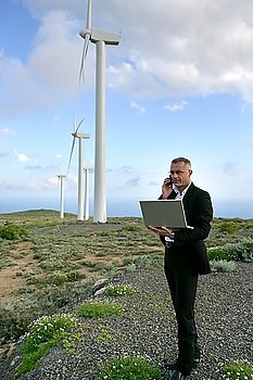 Businessman using a laptop on a windfarm