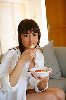 Portrait of a young woman eating a salad of fruits