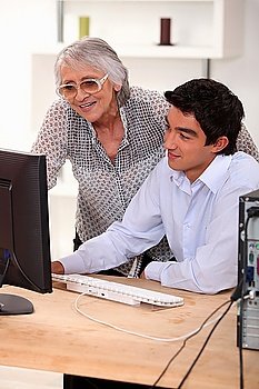 Old lady and young man sat by computer
