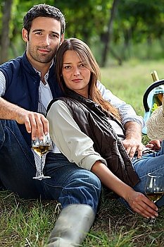 Couple having bottle of wine in field