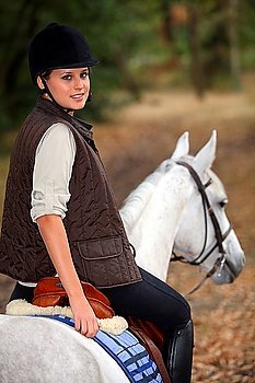Young woman riding a beautiful white horse